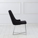 Front-facing side view of a modern glam black microfiber dining chair with a geometric base in an empty room