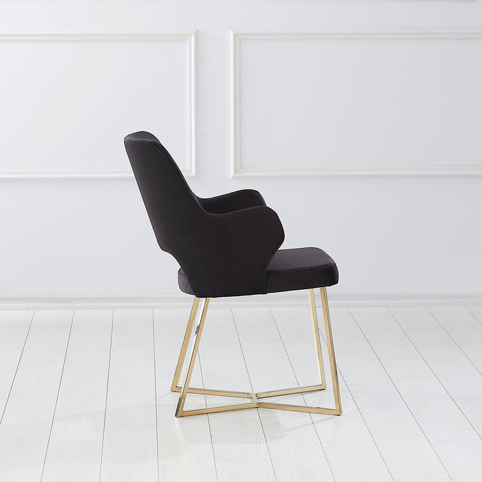 Front-facing side view of a modern glam black microfiber dining armchair with a geometric base in an empty room
