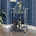 Left angled contemporary chrome and tempered glass serving cart with two shelves in a living space with accessories
