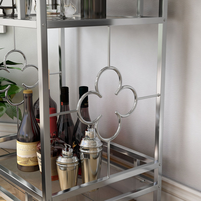 Detail shot contemporary chrome and tempered glass serving cart with quatrefoil accents in a living area with accessories