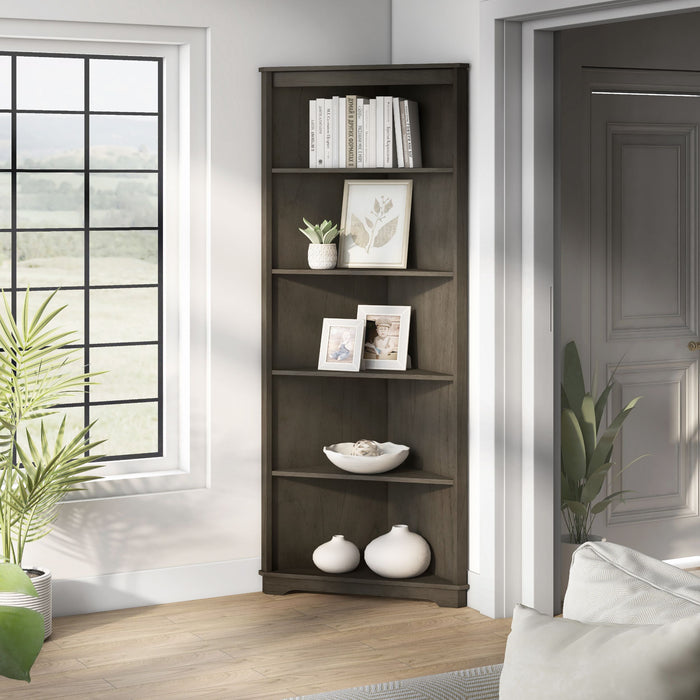 Left angled transitional antique gray poplar wood corner bookcase with five shelves in a living area with accessories