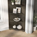 Left angled transitional antique gray poplar wood corner bookcase with five shelves in a living area with accessories