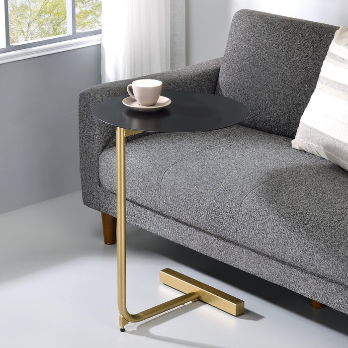 Right angled contemporary black and gold C-shaped side table in a living room with accessories