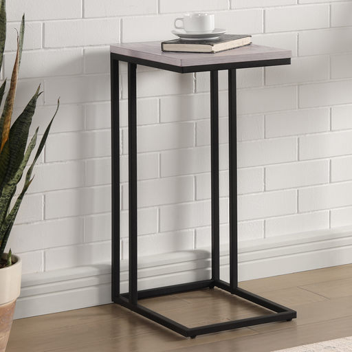 Left angled urban black and antique white C-shaped rectangular side table in a living area with accessories