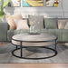 Front-facing contemporary gray and black round ottoman in a living room with accessories