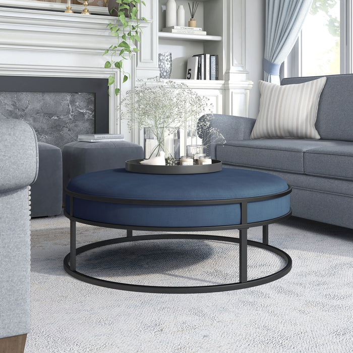 Left angled contemporary navy and black round ottoman in a living room with accessories
