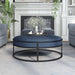 Front-facing contemporary navy and black round ottoman in a living room with accessories