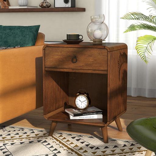 Left angled mid-century modern dark oak side table with single drawer and open bottom cabinet space decorated next to a sofa in a living room.