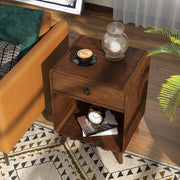 Left angled top-down mid-century modern dark oak side table with single drawer and open bottom cabinet space decorated next to a sofa in a living room.