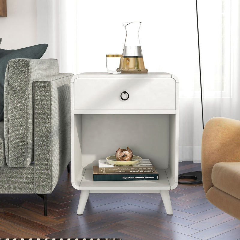 Front-facing mid-century modern antique white side table with single drawer and open bottom cabinet space decorated next to a sofa in a living room.