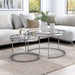 Right angled glam chrome and clear glass two-piece nesting tables in a living room with accessories