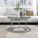 Front facing glam chrome and gray glass two-piece nesting tables, shown nested, in a living room with accessories