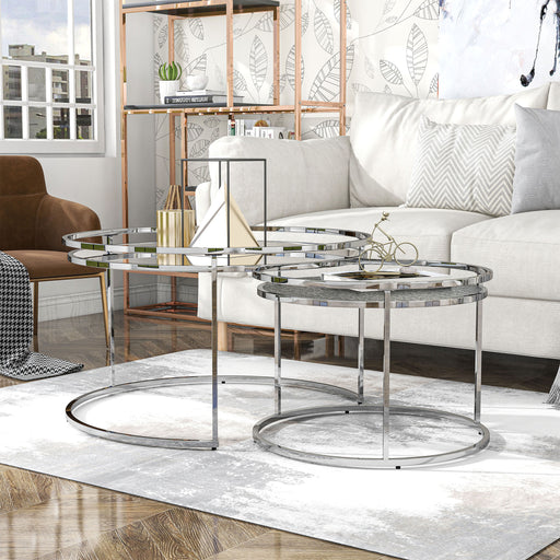 Left angled glam chrome and clear glass two-piece nesting tables in a living room with accessories