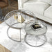 Left angled top view of glam chrome and clear glass two-piece nesting tables in a living room with accessories