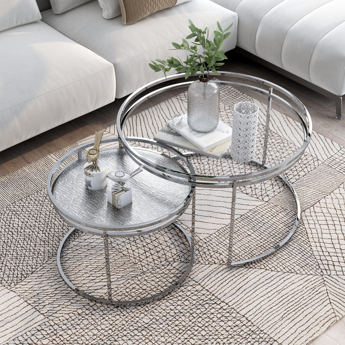 Right angled top view of glam chrome and clear glass two-piece nesting tables in a living room with accessories