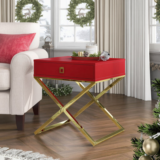 Red and gold end table in a classy living room. It sits next to beige seating with a red throw pillow. Christmas pine decorates the surrounding.