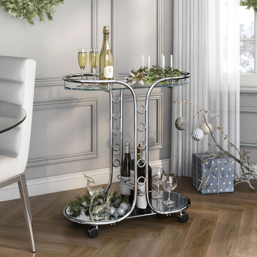 Silver and glass serving cart in a classy dining room. An advent candle display sits on its top shelf, while champagne and wine bottles are secured in the bottle rings of the bottom shelf.