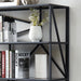 Left-angled close up modern geometric five-shelf etagere bookcase in black upper left corner detail in a contemporary living space with accessories