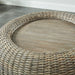 Top view close up coastal woven rattan look round accent table top detail on a gray tile floor