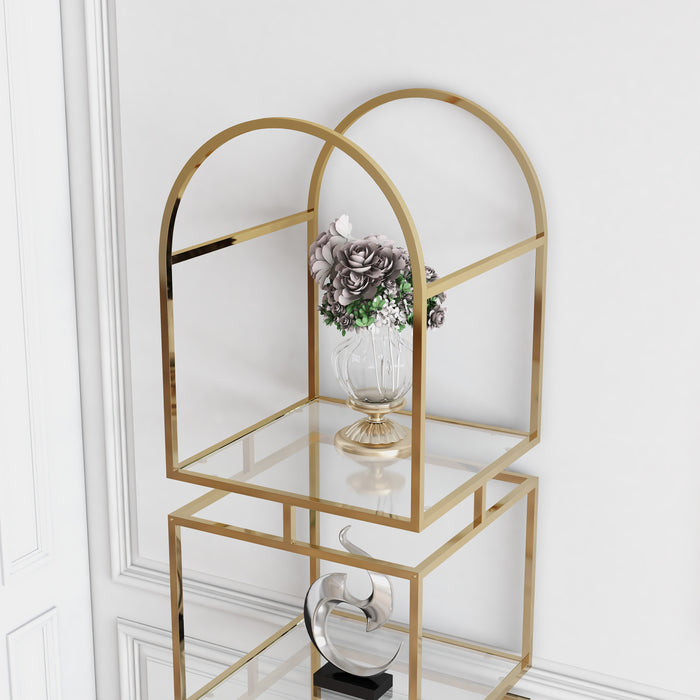 Left-facing modern gold arched bookcase decorated with accessories against white wall. Top-down detail of gold arched frame and clear glass shelf.