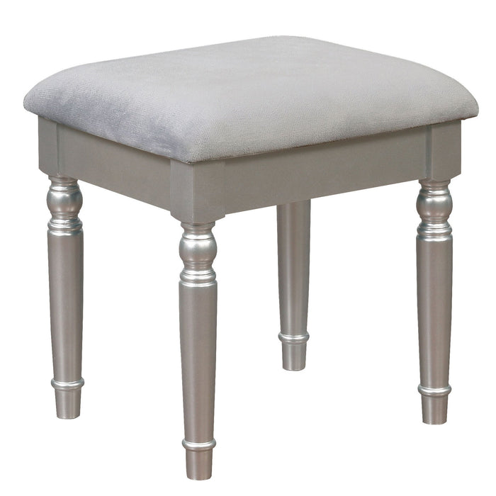 Right-angled silver vanity stool against a white background. Turned legs prop up a fabric-top seat.