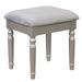 Right-angled silver vanity stool against a white background. Turned legs prop up a fabric-top seat.