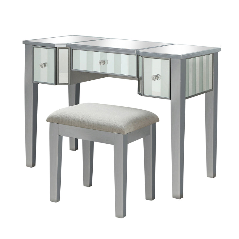 Left-angled silver vanity set against a white background. This vanity table features a mirrored tabletop and stripe frosted mirrored drawers with acrylic knobs. It stands on long tapered legs to match the fabric-top stool.