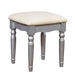 Right-angled silver vanity stool against a white background. Turned legs and a curved skirt prop up a fabric-top seat.