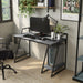 Angled right-facing  view of urban light gray and matte black steel writing desk with accessories