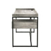 Side-facing view of industrial light gray and matte black steel and particle board writing desk in living space with accessories