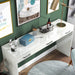 Angled semi-top down view of glam luminous white pine wood three-drawer vanity table in living space with accessories