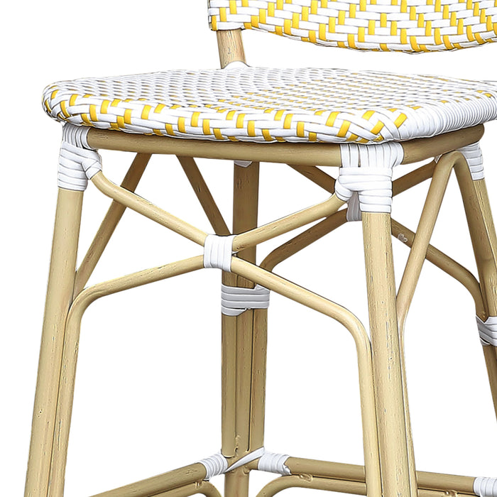 Detail shot of a yellow and white chevron patterned wicker patio bar chair with a natural tone frame.