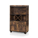 Left-angled distressed wood wine bar cabinet against a white background. Two hanging stemware racks, an X wine rack and barndoor cabinets create a rustic look.