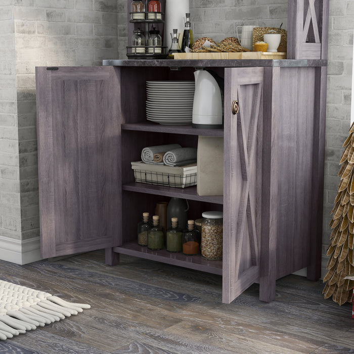 The barnhouse-inspired lower cabinet doors of a dark grey bakers rack open to reveal plates, linens, and spices.