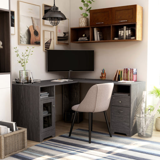 Slightly angled front-facing view of modern dark gray finish L-shaped desk with storage in workspace with accessories
