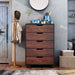 Front-facing vintage walnut 5-drawer chest in a rustic bedroom. A tissue box, lotions, and cosmetics sit on the rustic plank-style paneling.