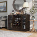 Left-angled espresso wine bar cabinet in a traditional home. Wine glasses hang on the 2 metal stemware racks, while 10 wine bottles are stored in the wine rack. Flanking these are two glass-paneled cabinets with chinaware and a decanter stored on the six shelves. Pink rose, a wine bottle, and wine glasses sit on the left of the tabletop. A bowl of peaches, a frame, and a lamp sit on the right. Above the sideboard is a round mirror.