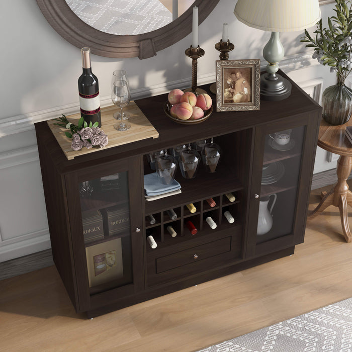 Top view of an espresso wine bar cabinet in a traditional home. Wine glasses hang on the 2 metal stemware racks, while 10 wine bottles are stored in the wine rack. Flanking these are two glass-paneled cabinets with chinaware and a decanter stored on the six shelves. Pink rose, a wine bottle, and wine glasses sit on the left of the tabletop. A bowl of peaches, a frame, and a lamp sit on the right. Above the sideboard is a round mirror.