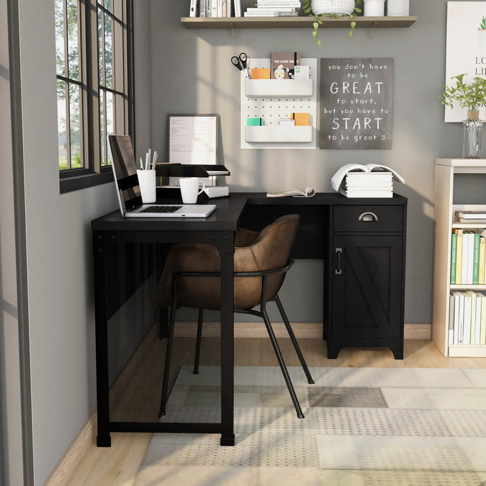 Straight-facing L-shaped desk in the corner of a modern farmhouse-style home office. The black desk sits against grey walls. Above one side of the desk is a black-trimmed window and above the right side is a taupe shelf with books, plants, and decor. A wall stationary and an inspirational quote hang on the wall just below the shelf. This desk holds a laptop, file tray, and other office-related things. A brown leather chair sits at the desk with a low back and black flared legs.