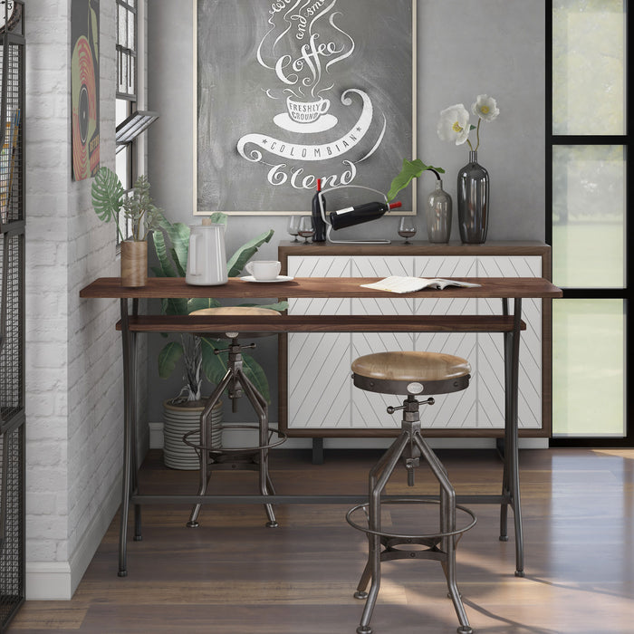 Front-facing modern toasted barnwood and metal counter height table with a trestle base in a dining area with accessories