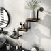Left-angled industrial staggered three-tier wall shelf with pipe-style framing and reclaimed oak surfaces in an urban bathroom