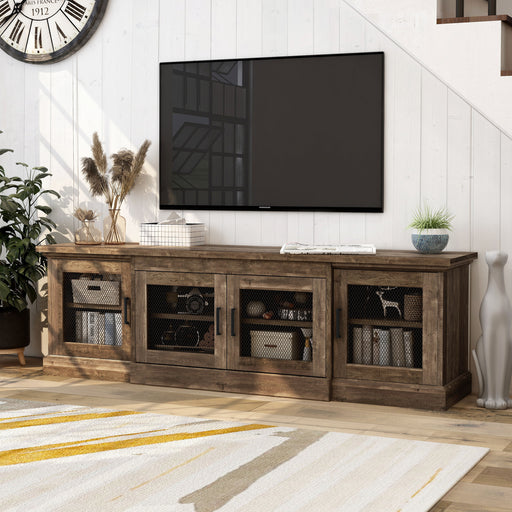Left-angled rustic four-door TV stand with a reclaimed oak finish and metal mesh door inserts in a modern farmhouse living room with accessories