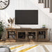 Front-facing rustic four-door TV stand with a reclaimed oak finish and metal mesh door inserts in a modern farmhouse living room with accessories