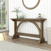 Left-angled rustic reclaimed oak wood finish console table with arch braces in a modern farmhouse living space with accessories