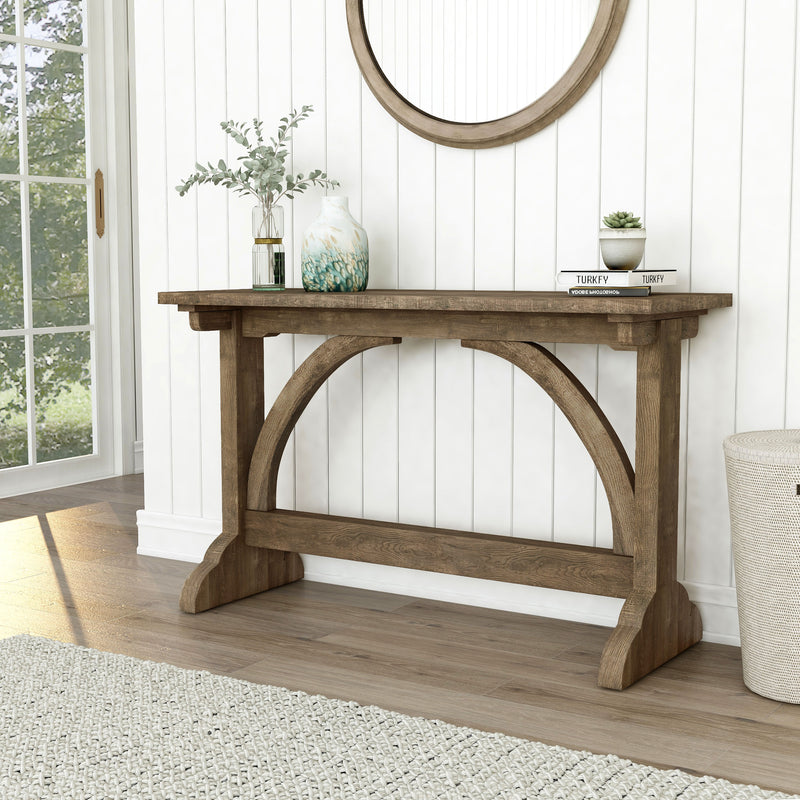 Left-angled rustic reclaimed oak wood finish console table with arch braces in a modern farmhouse living space with accessories