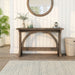 Front-facing rustic reclaimed oak wood finish console table with arch braces in a modern farmhouse living space with accessories