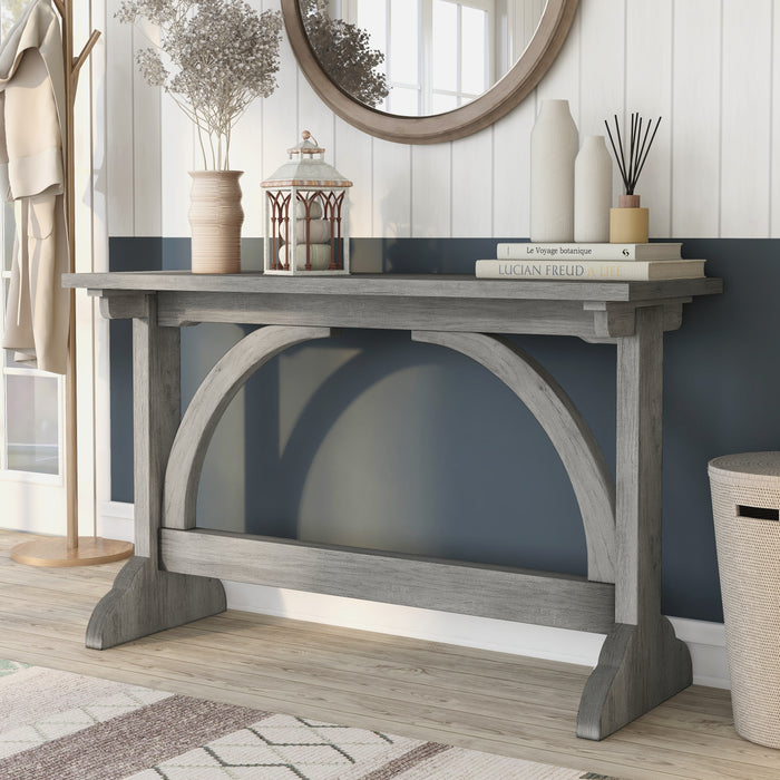 Left-angled rustic vintage gray oak wood finish console table with arch braces in a modern farmhouse living space with accessories