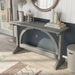 Left-angled top view rustic vintage gray oak wood finish console table with arch braces in a modern farmhouse living space with accessories