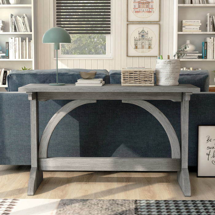 Front-facing rustic vintage gray oak wood finish console table with arch braces against a sofa in a modern farmhouse living space with accessories