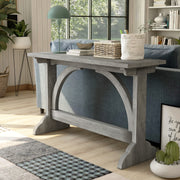 Left-angled vintage grey oak wood finish console table with arch braces in a modern farmhouse living space with accessories